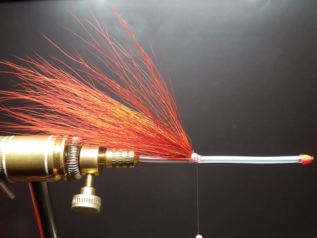 1. After fixing the tube in your vice, fix a first pinch of orange bucktail with your thread, leaving 4 to 5 cm of the sleeve free, for sliding the silicon sleeve which serves to block your dressing. Apply a generous amount of superglue.