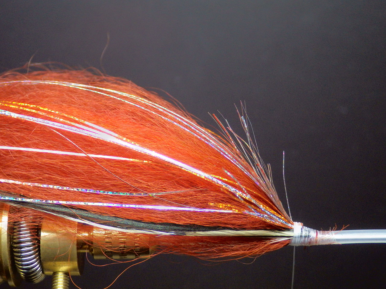 8. If you wish, you can tie in wing feathers (preferably in a colour which creates a contrast) at this stage, they will help the streamer’s swim. Tie them in at the same length as the holographic fibres. Apply enough superglue at the fixing knot.